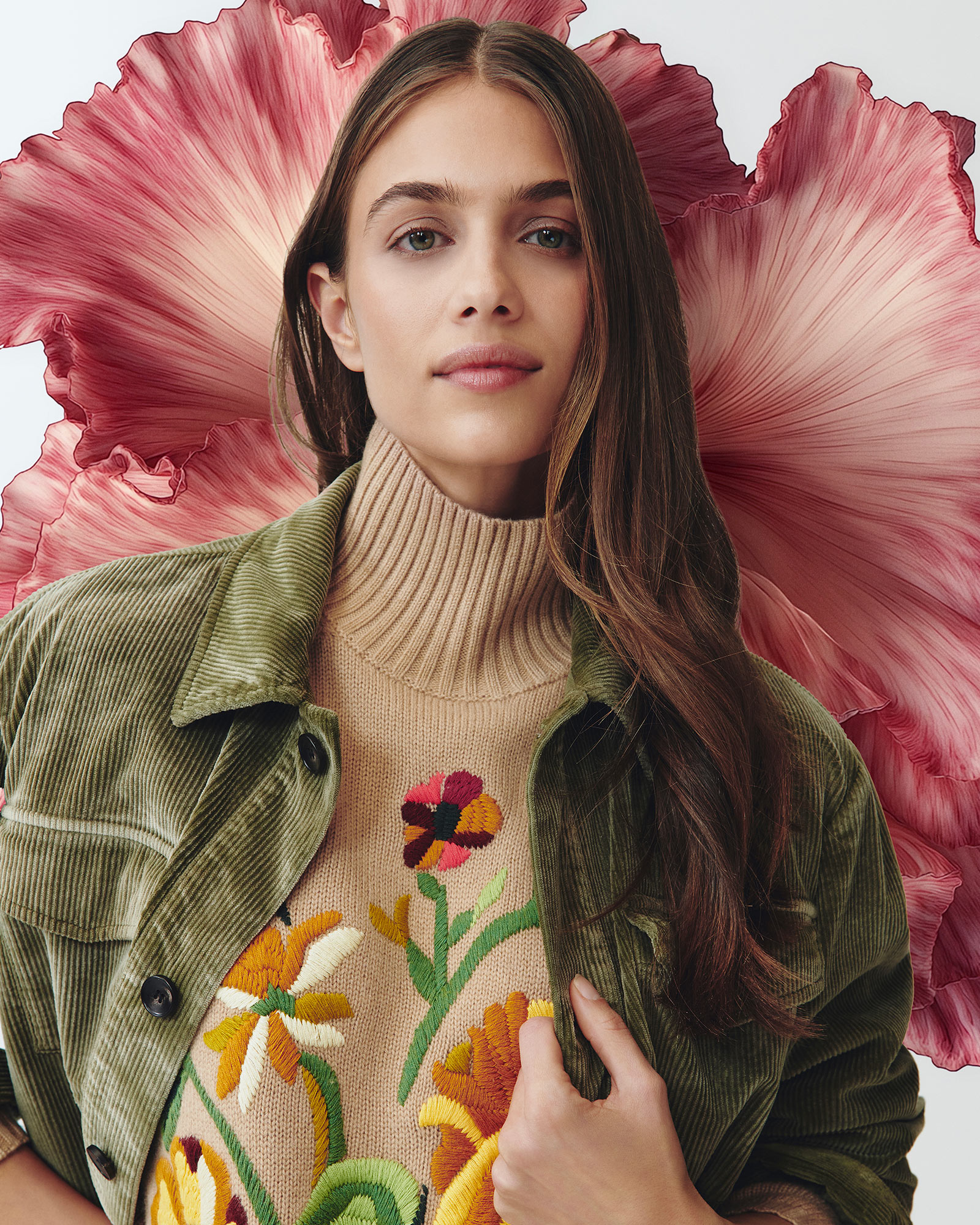 Woman wearing an embroidered floral sweater and green jacket.