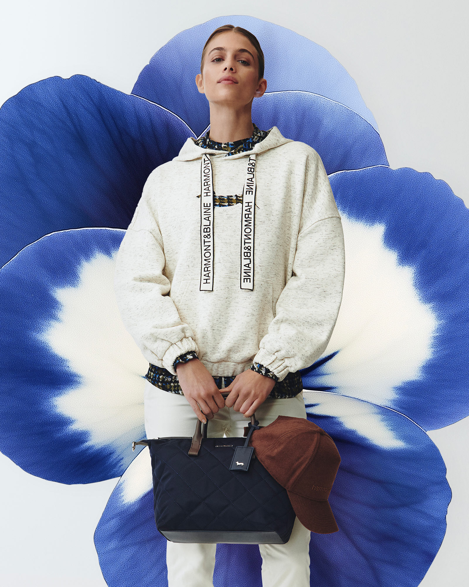 Woman wearing a white hoodie with logo details and quilted bag.