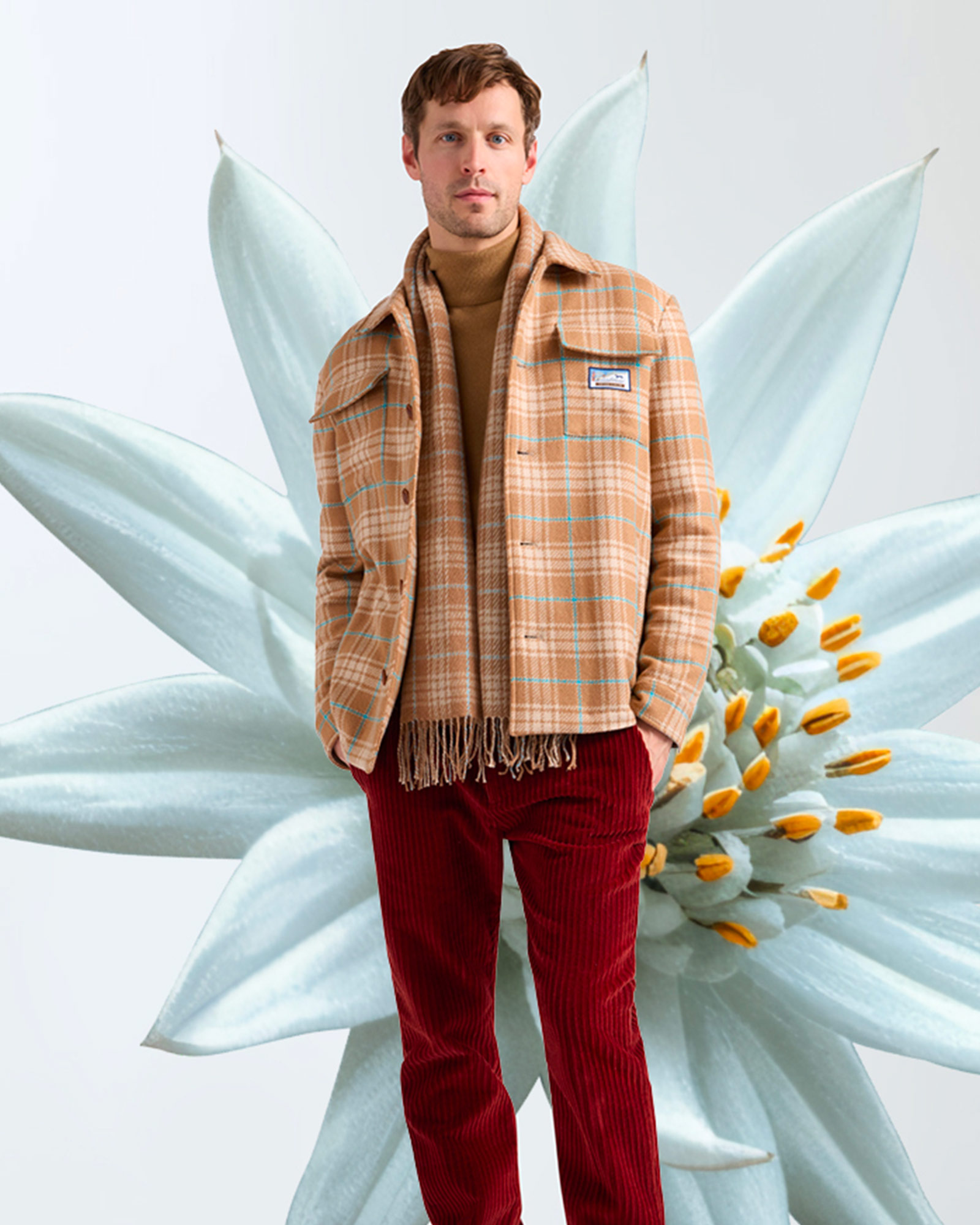 Man wearing beige checked overshirt and red corduroy trousers.