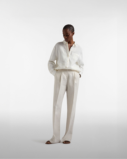 Donna con gilet in tweed grigio e camicia fantasia con pantaloni bianchi