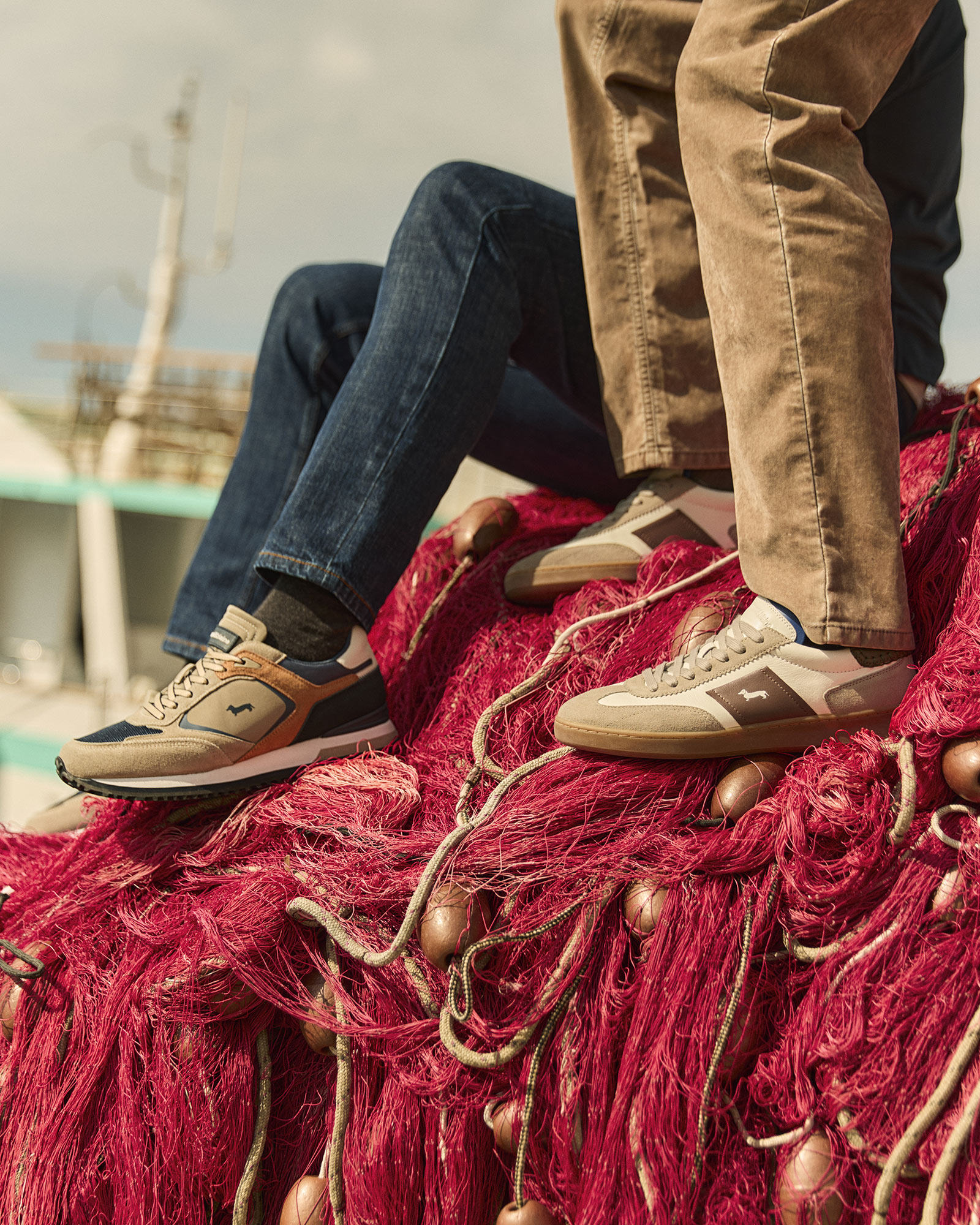 Dettaglio di sneakers beige e marroni indossate con jeans e pantaloni color sabbia