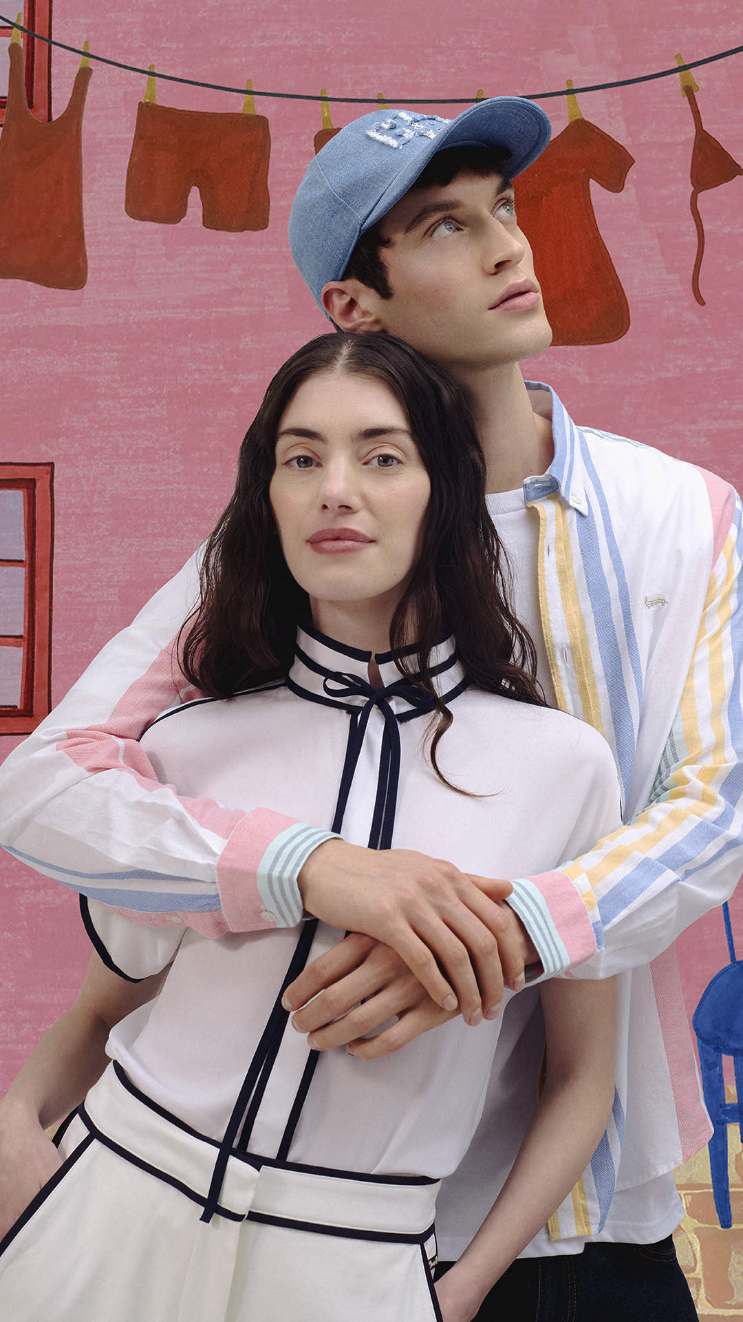 Uomo e donna con camicie a righe colorate e beachwear, davanti a un’illustrazione di piscina con palme — atmosfera vivace e audace dei saldi estivi.