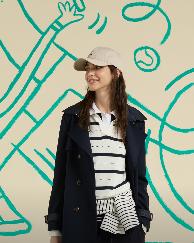 Donna con gilet in tweed grigio e camicia fantasia con pantaloni bianchi