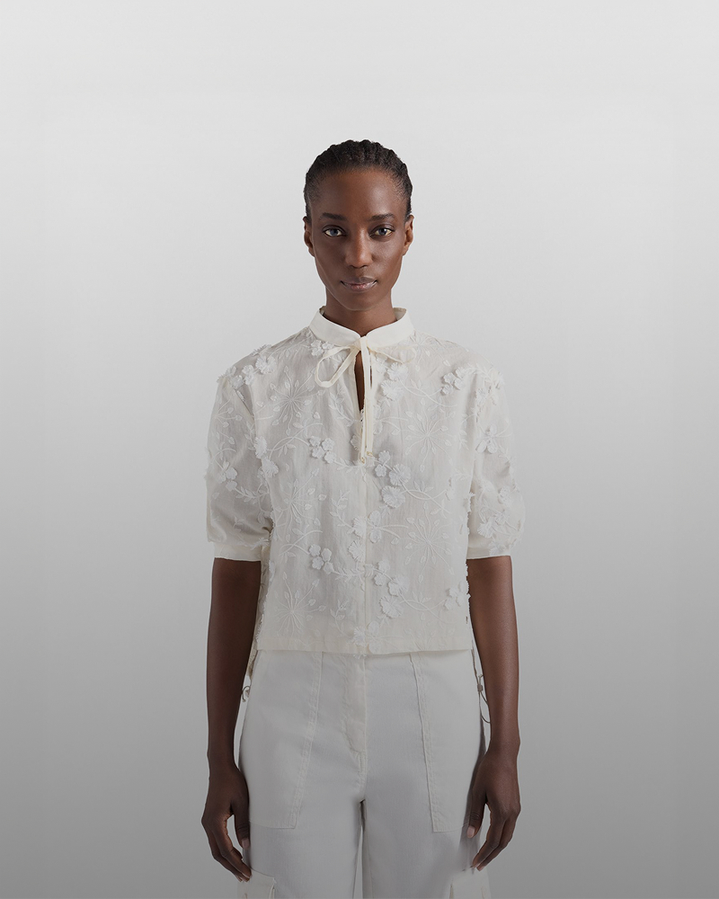 Woman wearing cream bomber jacket with striped trim and navy blue trousers