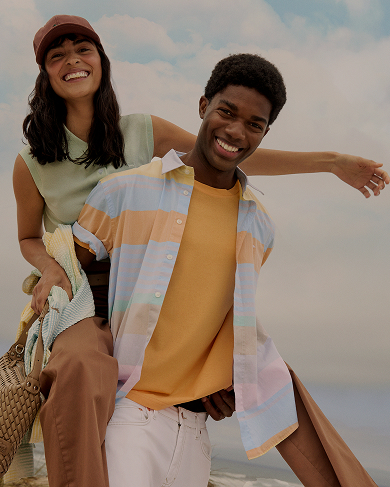 Coppia in spiaggia con polo a righe e cappellini da baseball