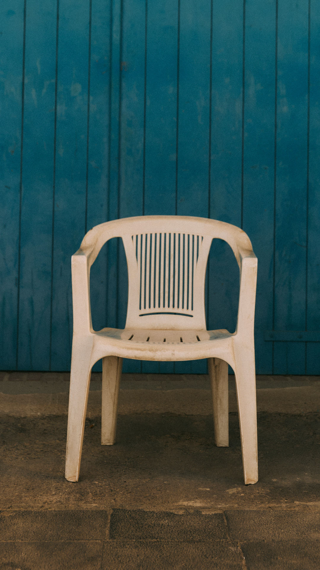 White plastic chair in front of a blue wall.