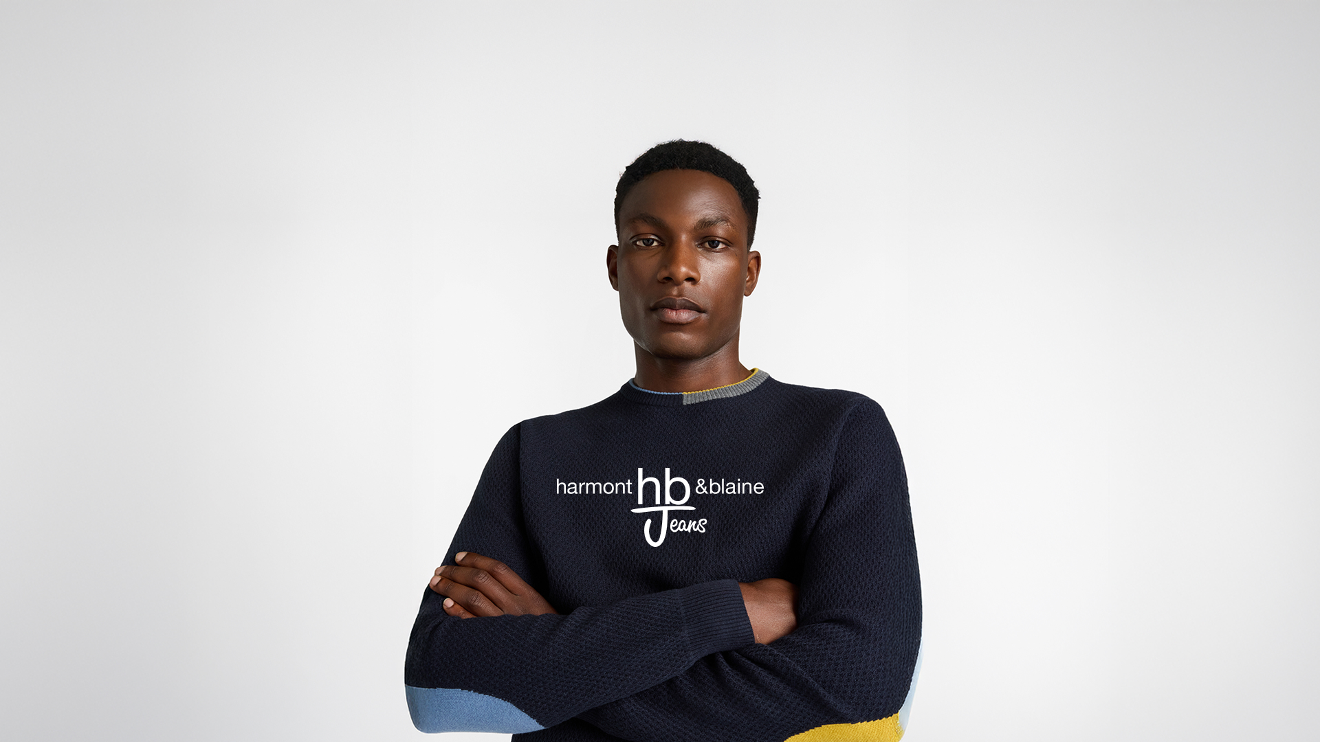 Felpa blu HBJ con logo ricamato e jeans scuri, immagine promozionale per i saldi HB Jeans.