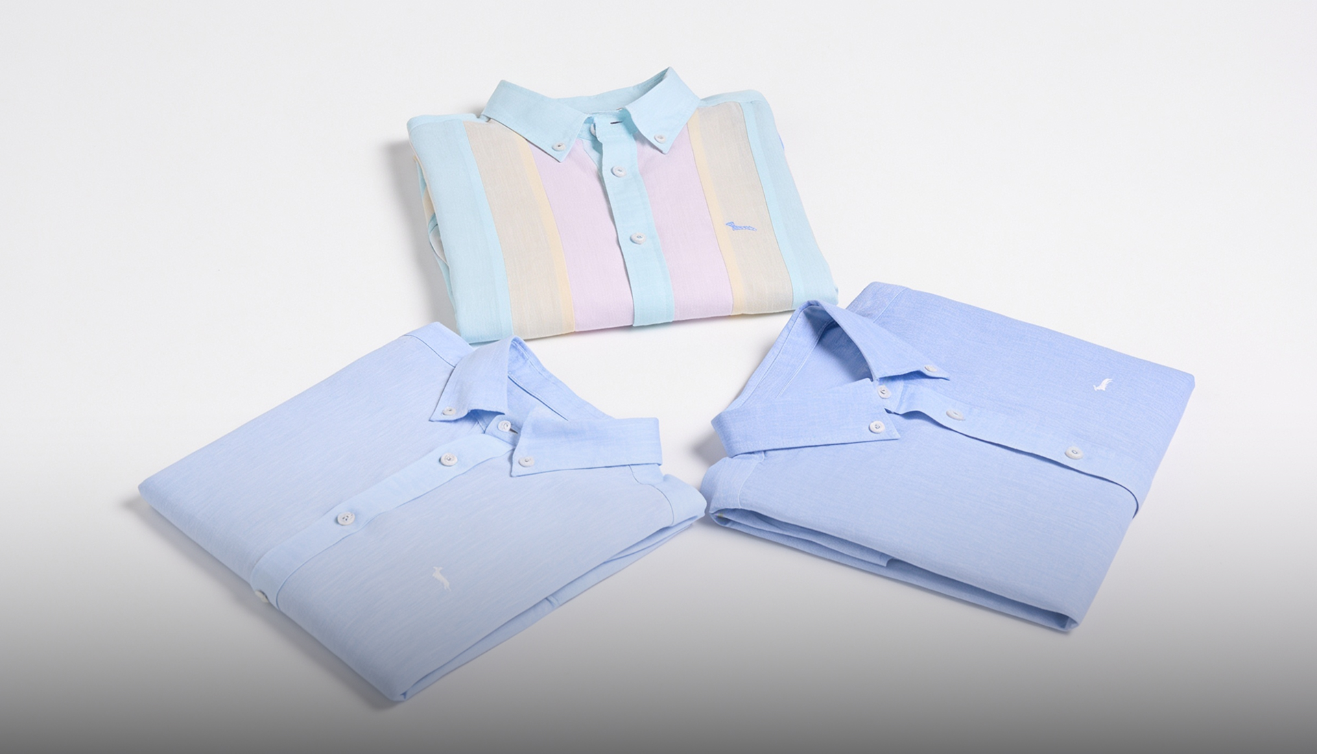 tre camicie da uomo ripiegate disposte a triangolo su sfondo bianco. in basso compare il testo descrittivo the italian resort style con i dettagli sulla collezione e la chiamata all'azione scopri le camicie.
