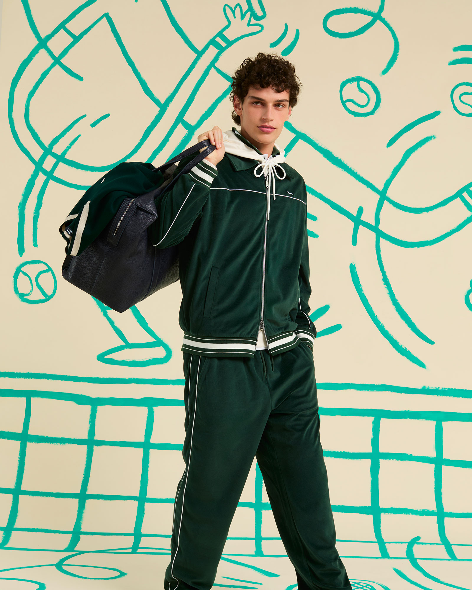 Man wearing green tracksuit with white piping and black sports bag