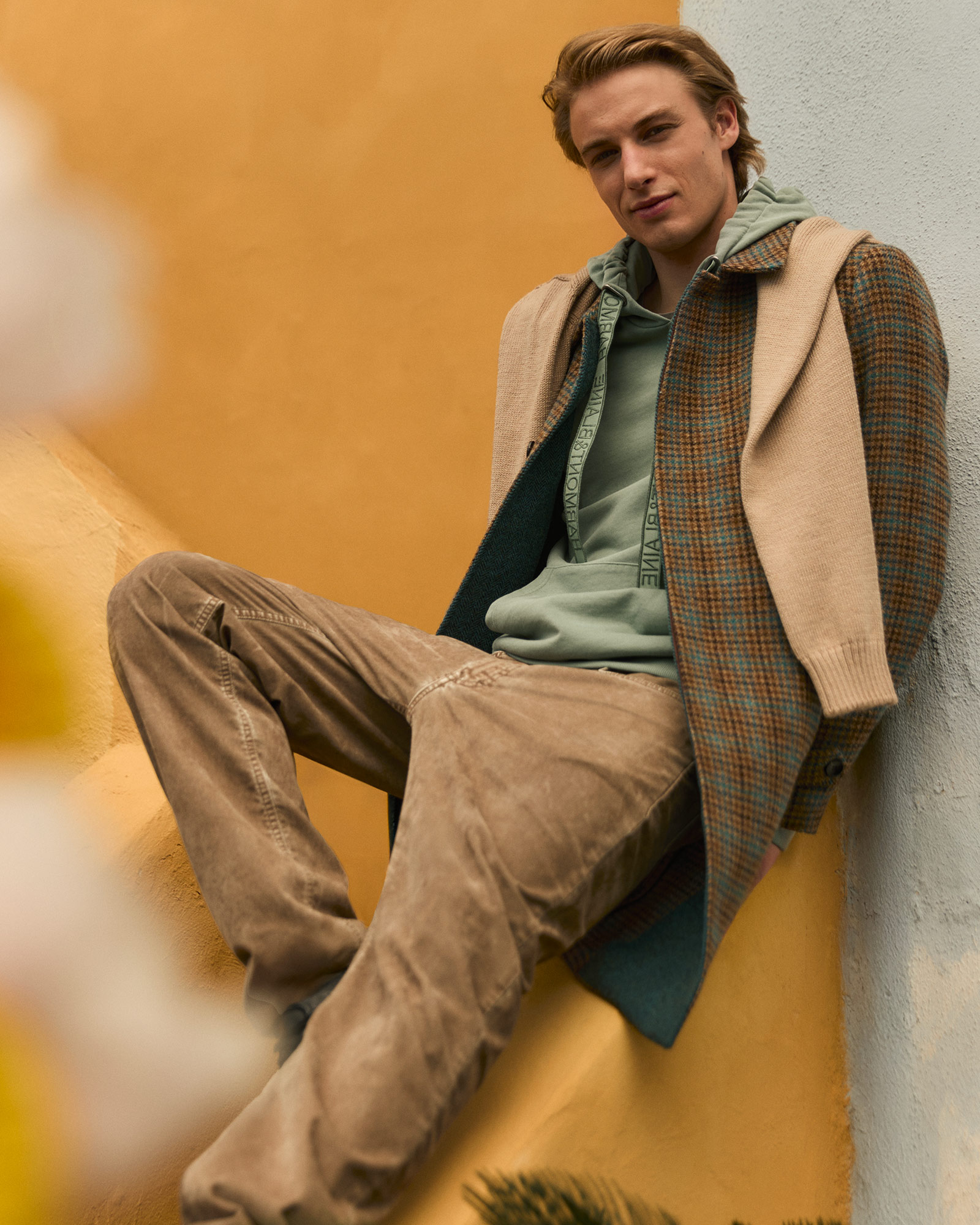 Uomo con giacca pied-de-poule e felpa con cappuccio verde salvia
