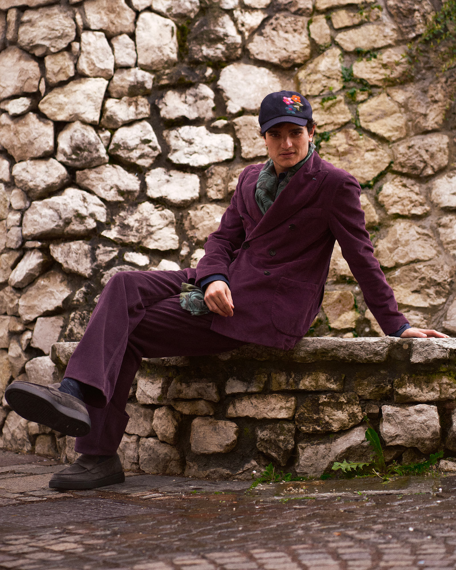 Person sitting on a stone bench in front of a stone wall