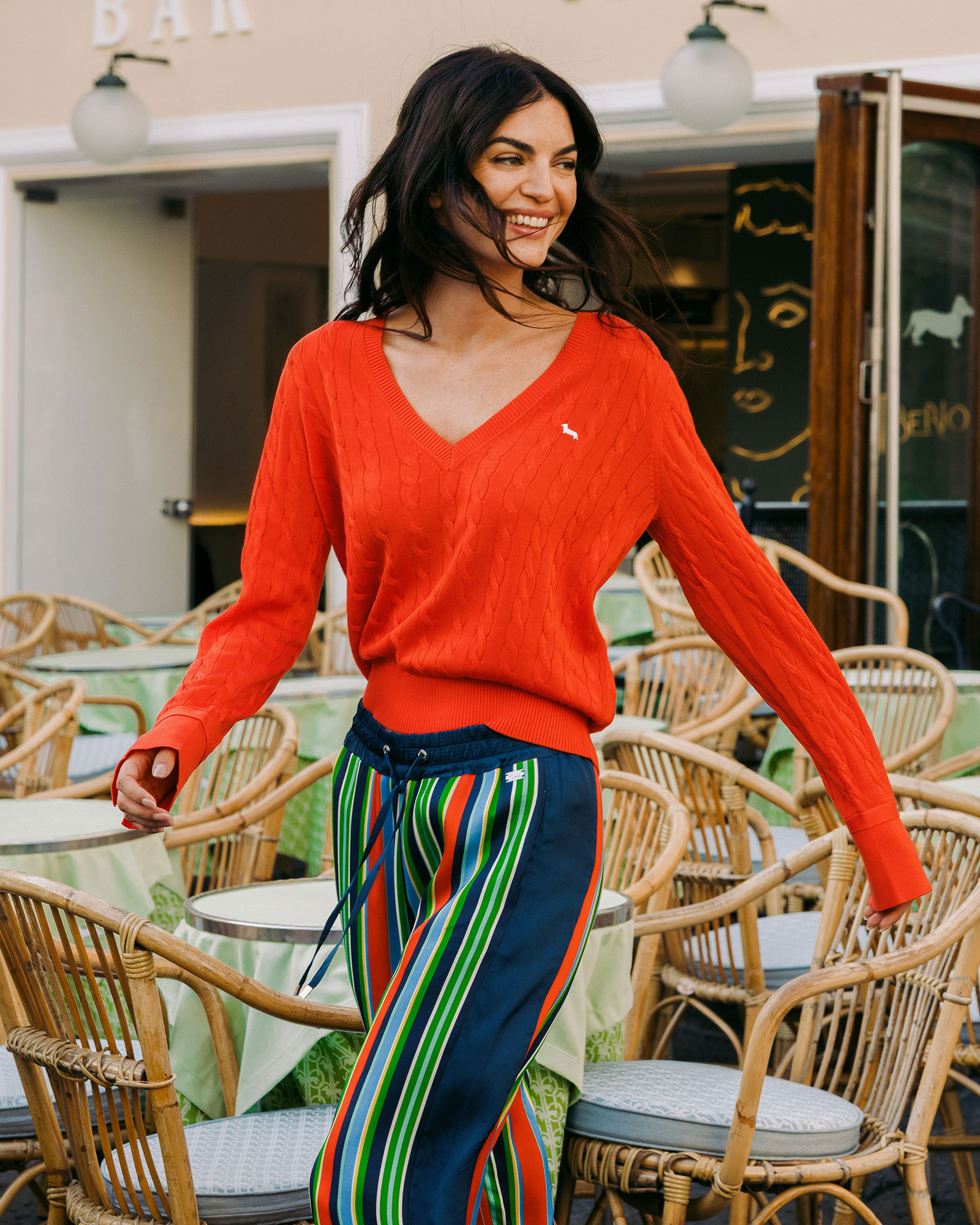 Donna con maglia rossa a scollo a V e pantaloni a righe colorate dal look vivace