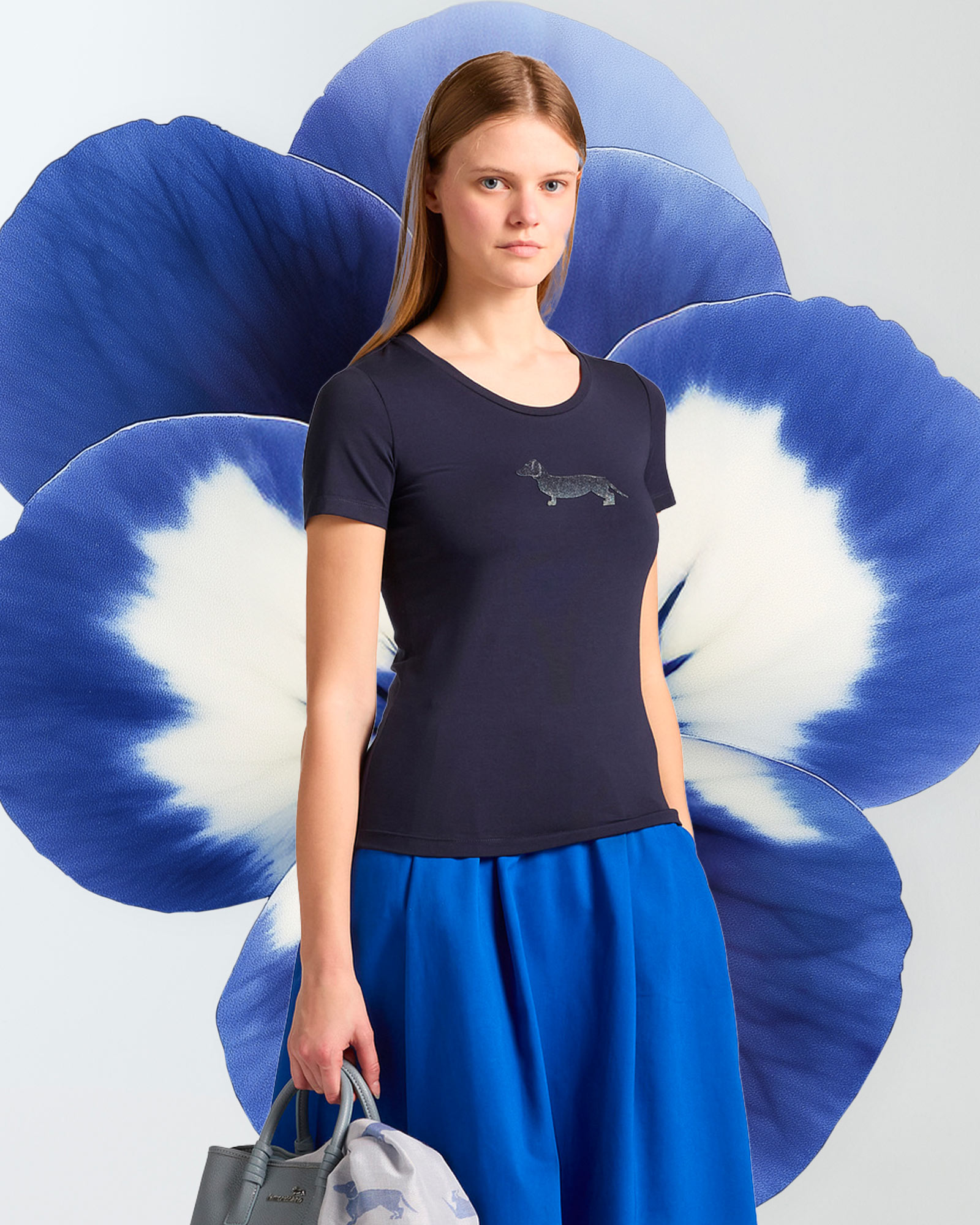 Woman wearing a dark blue t-shirt with logo and blue skirt.