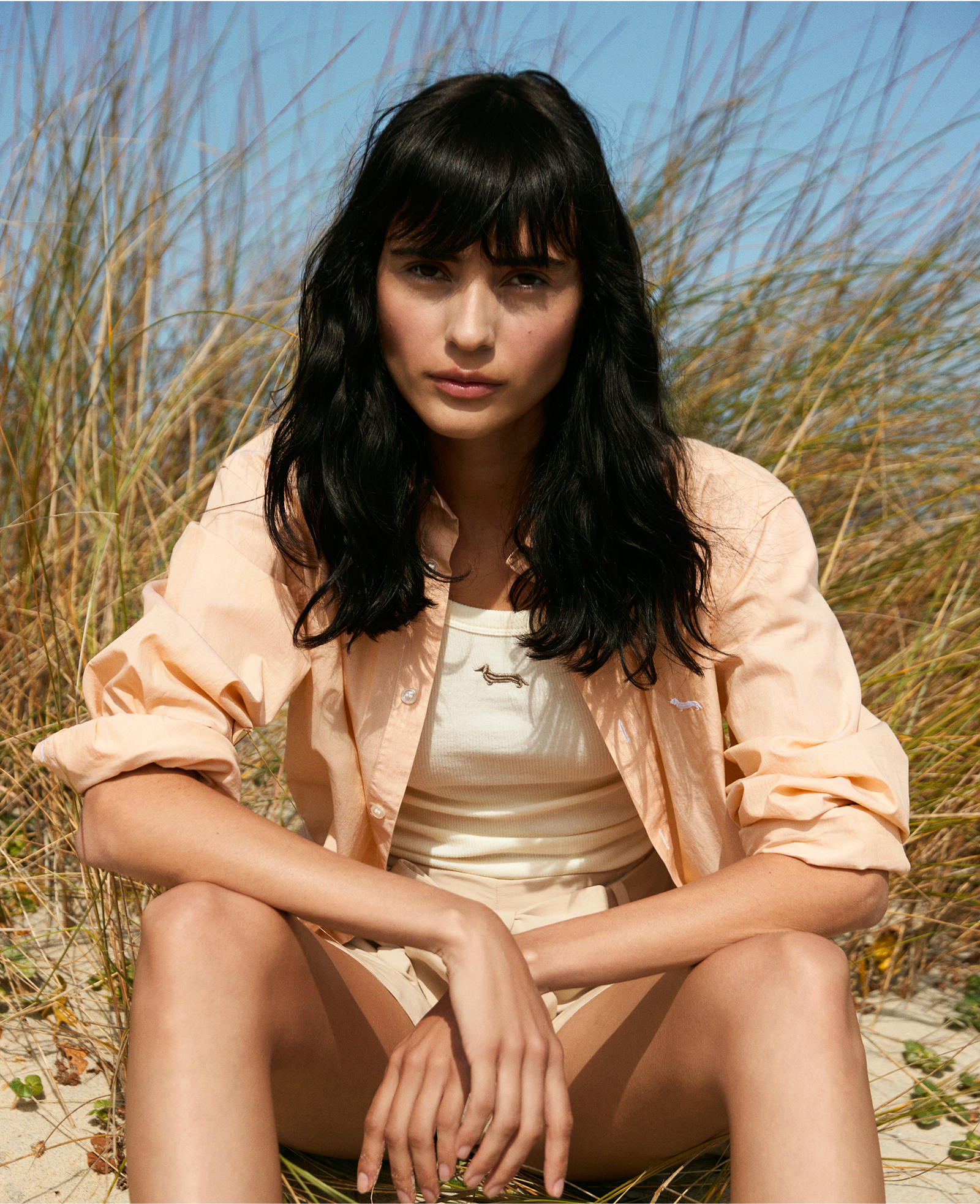 Donna con gilet in tweed grigio e camicia fantasia con pantaloni bianchi