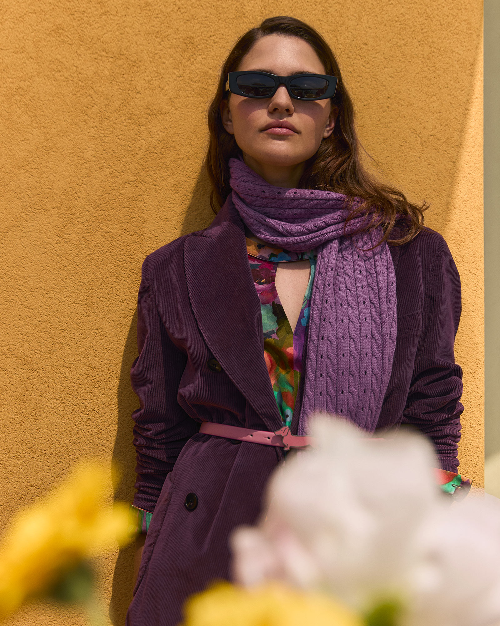 Fashion accessories on table, ochre wall behind.