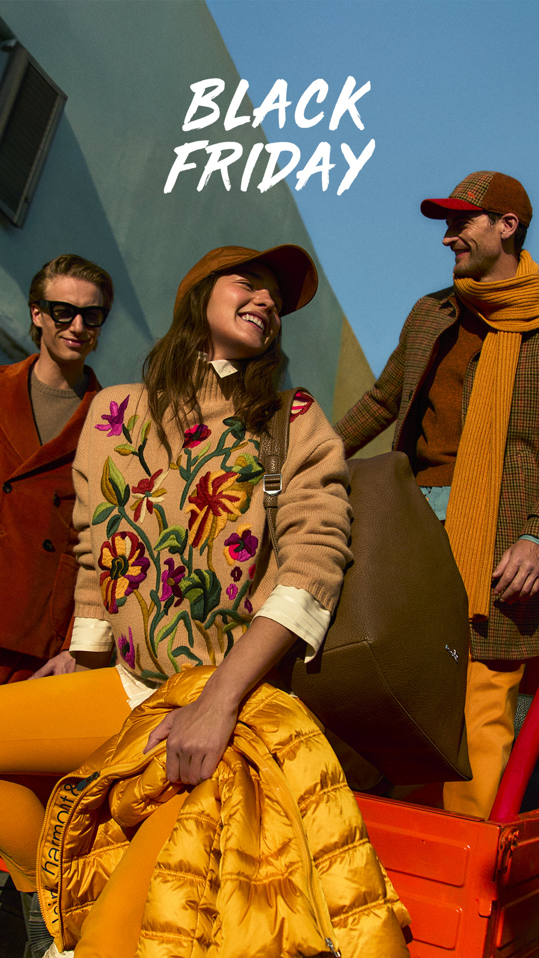 Pareja con abrigos de invierno frente a una gran flor azul.