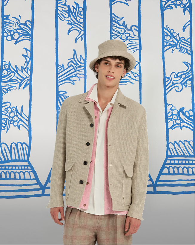 man in a bright blue linen jacket, vertically striped shirt, and jeans poses in front of a background with drawn blue columns. at the bottom, the text summer comfort and the call to action discover the jackets appear.
