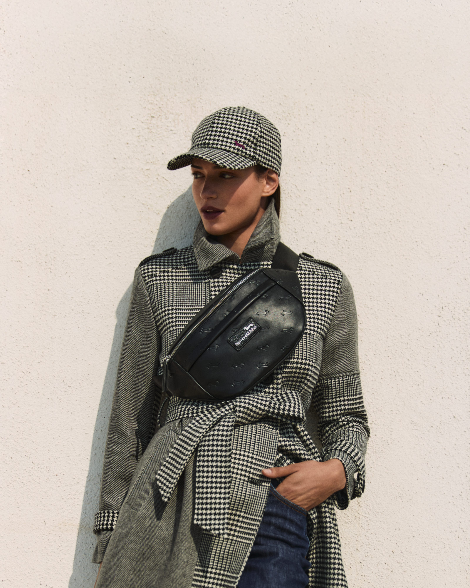 Mujer con abrigo de pata de gallo y bolso negro cruzado.