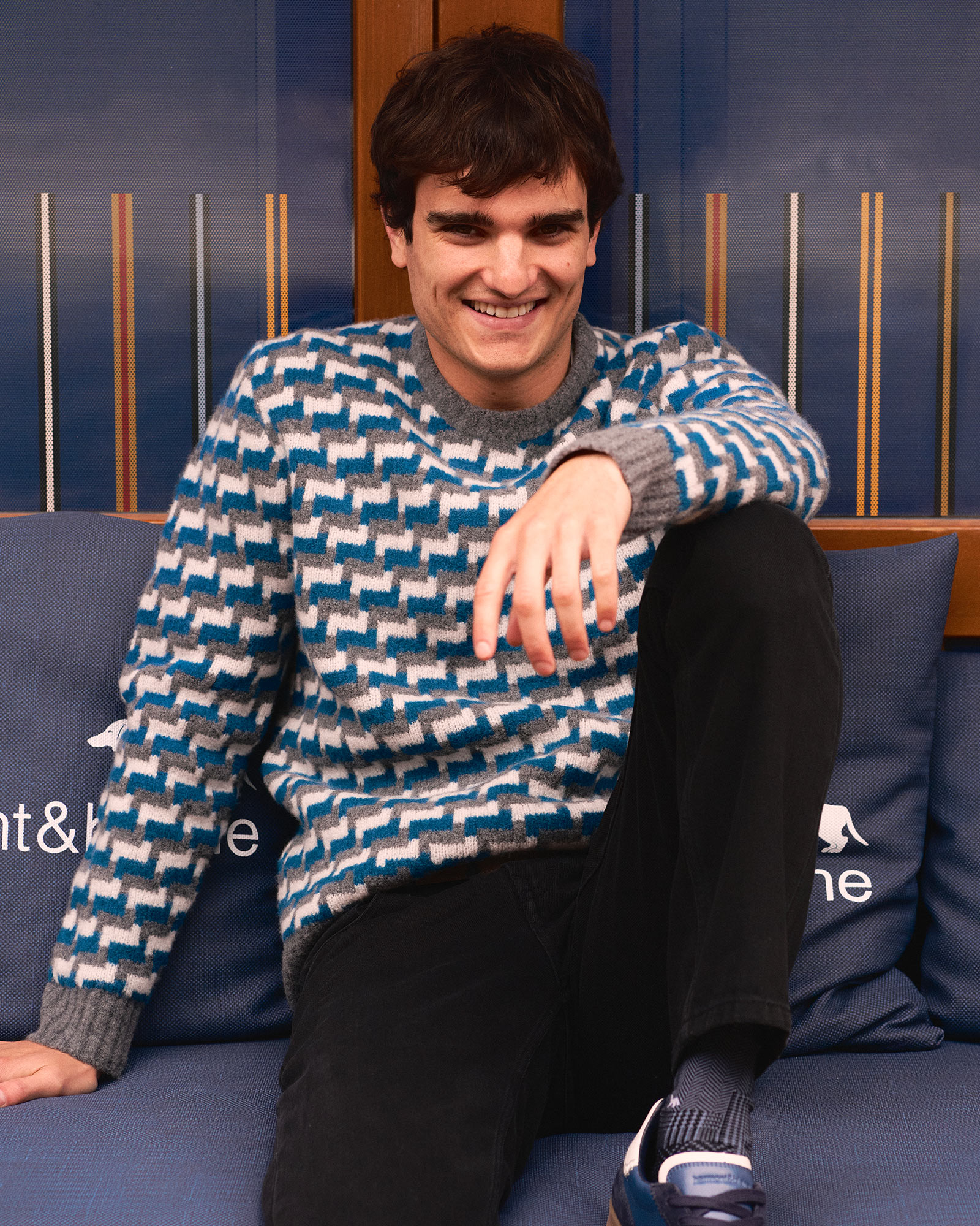 Person sitting on a blue sofa with cushions, wooden background