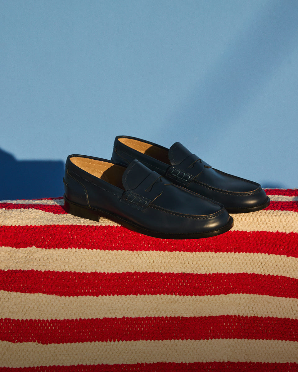 Black loafers on a cream and red striped cloth