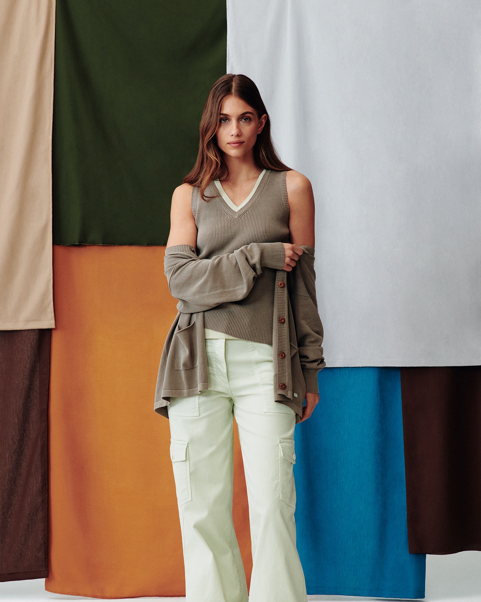 Modella con top a maglia senza maniche e cardigan verde oliva, pantaloni cargo verde chiaro.