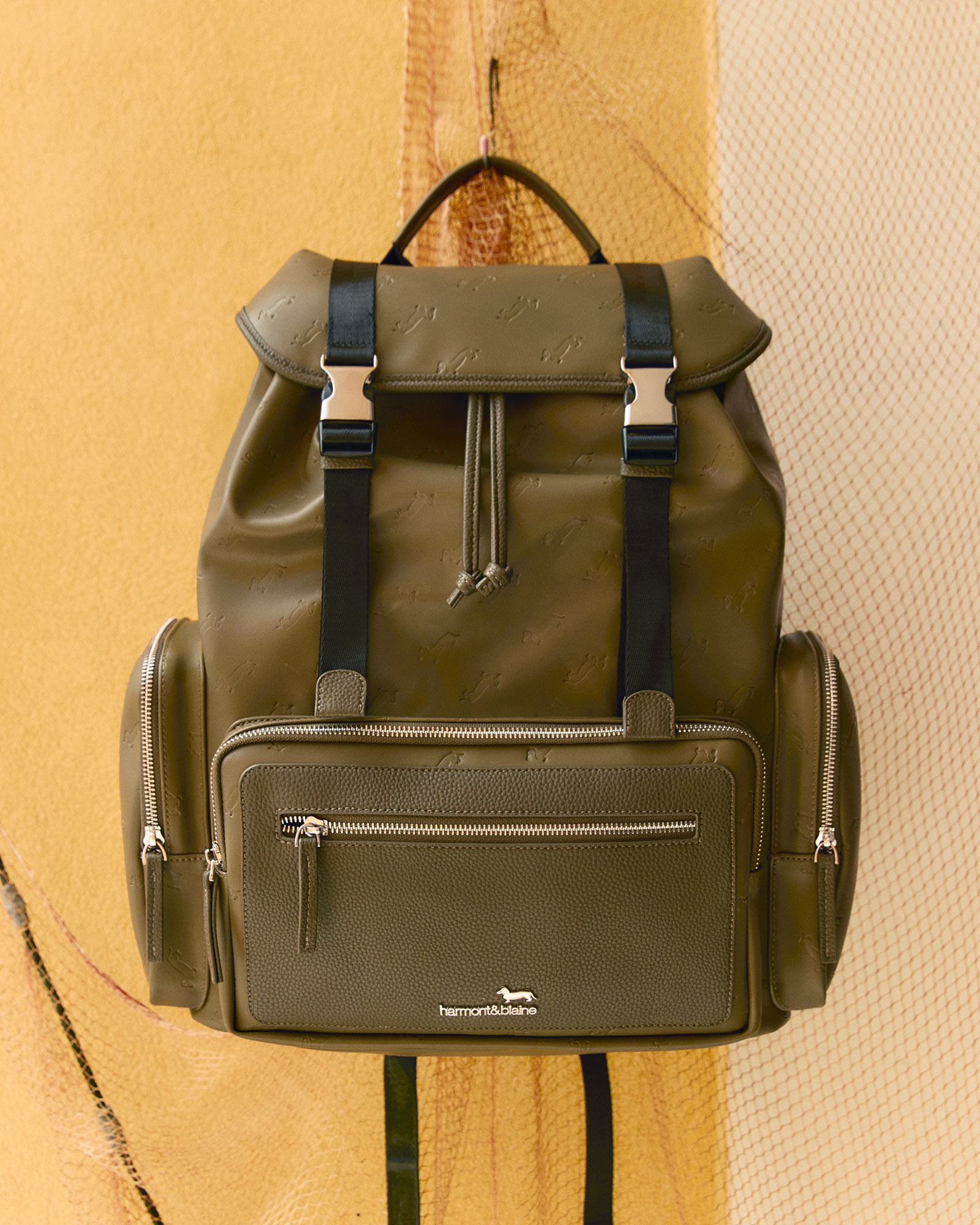 Green backpack with front and side leather pockets.