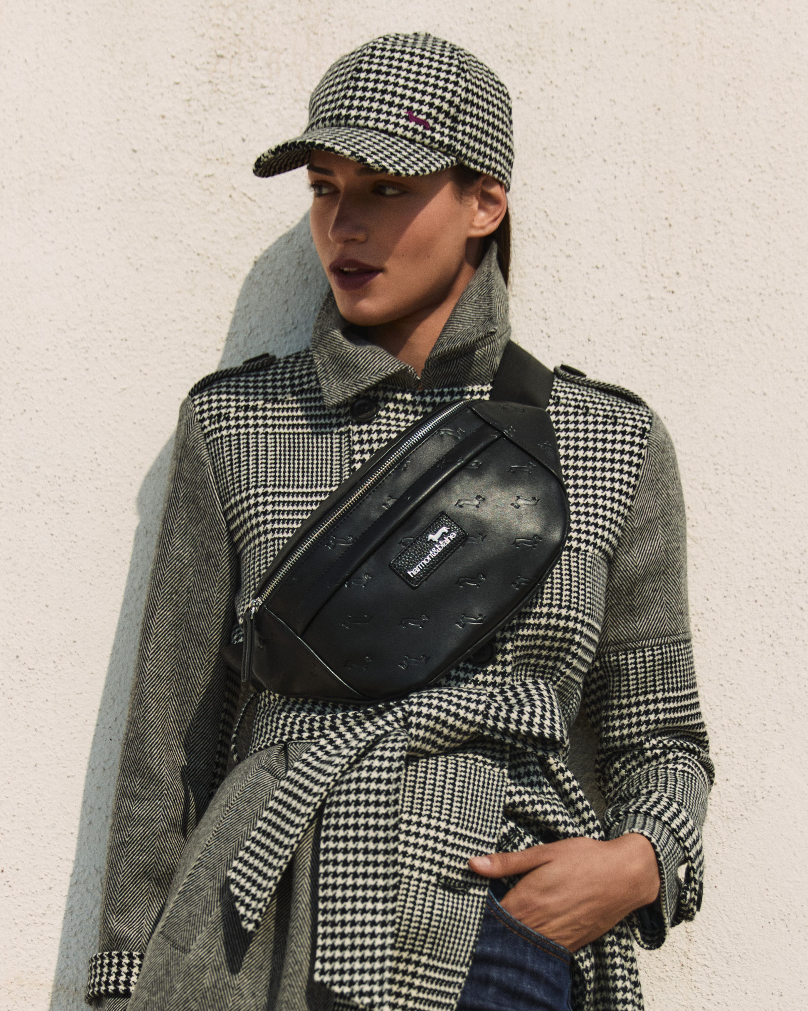 Woman wearing a houndstooth coat and black crossbody bag.