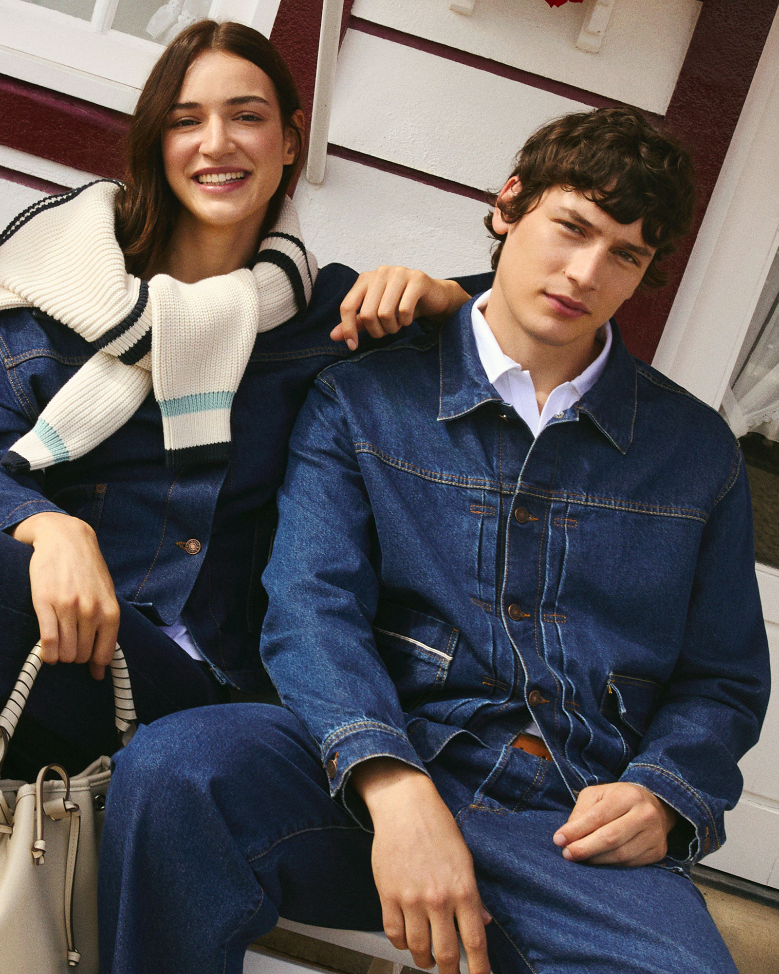 Woman and man in full denim; she wears a striped knit over the shoulders, he wears denim jacket and pants