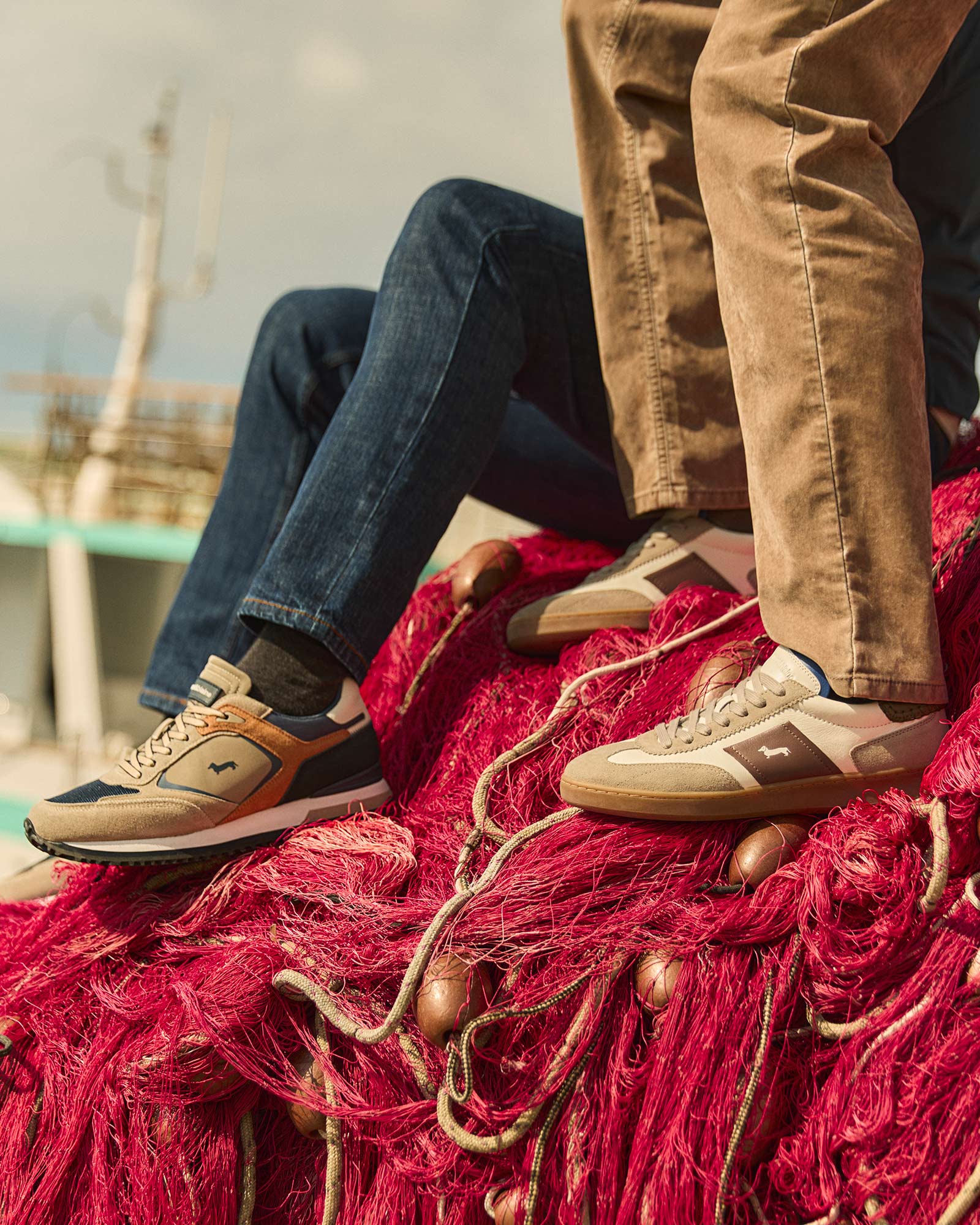 Zapatillas beige y azules usadas por dos personas sentadas sobre una red roja.