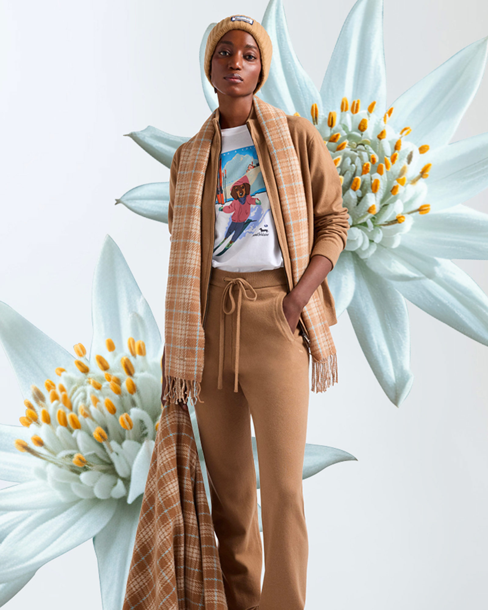 Woman wearing beige set with printed t-shirt, beige checked scarf and matching beanie.