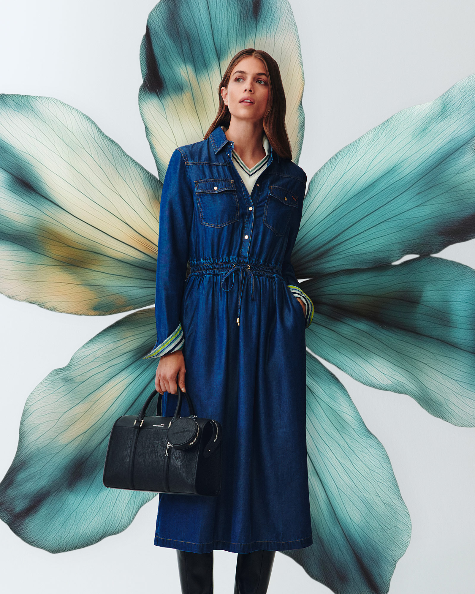 Woman wearing a blue denim dress in front of a large teal flower.