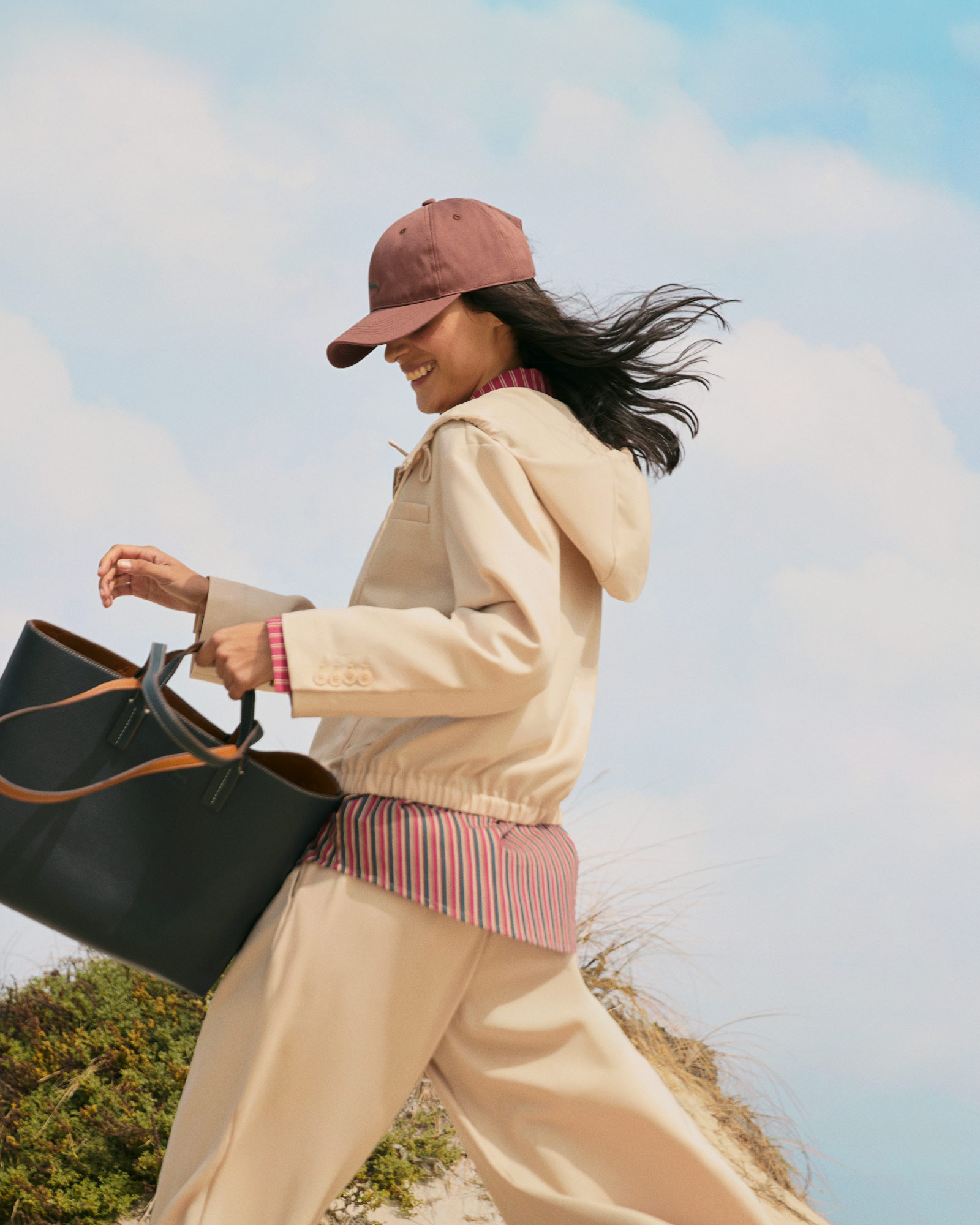 Donna con giacca a vento beige e camicia a righe con cappellino rosa