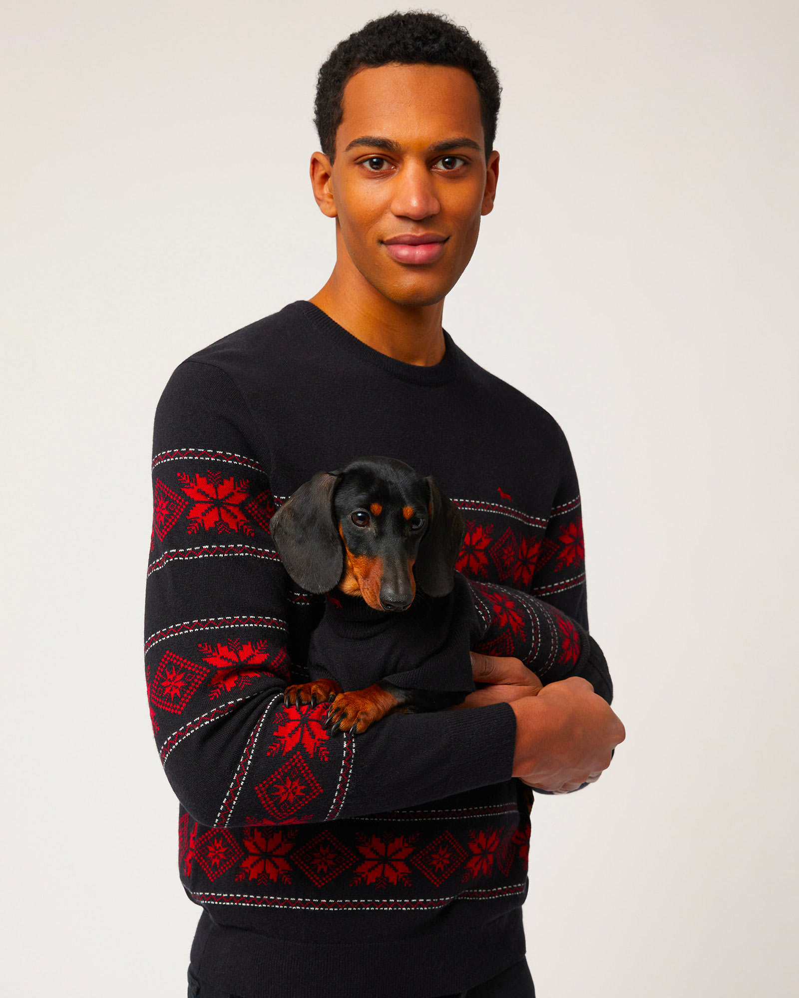 Dark sweater with pattern, light neutral backdrop.