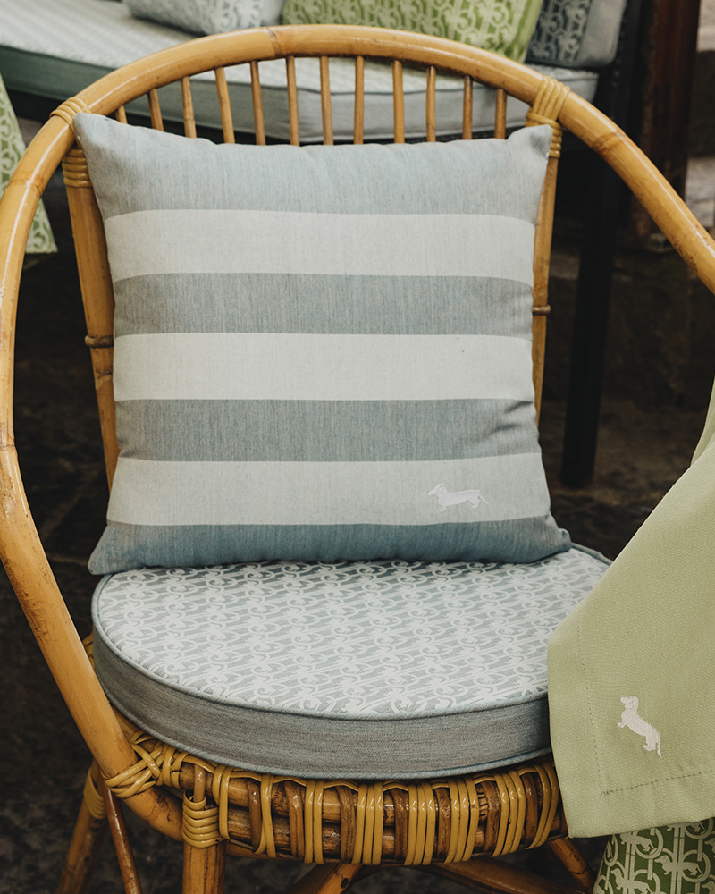 Sedia in rattan con cuscino a righe e logo Harmont & Blaine.