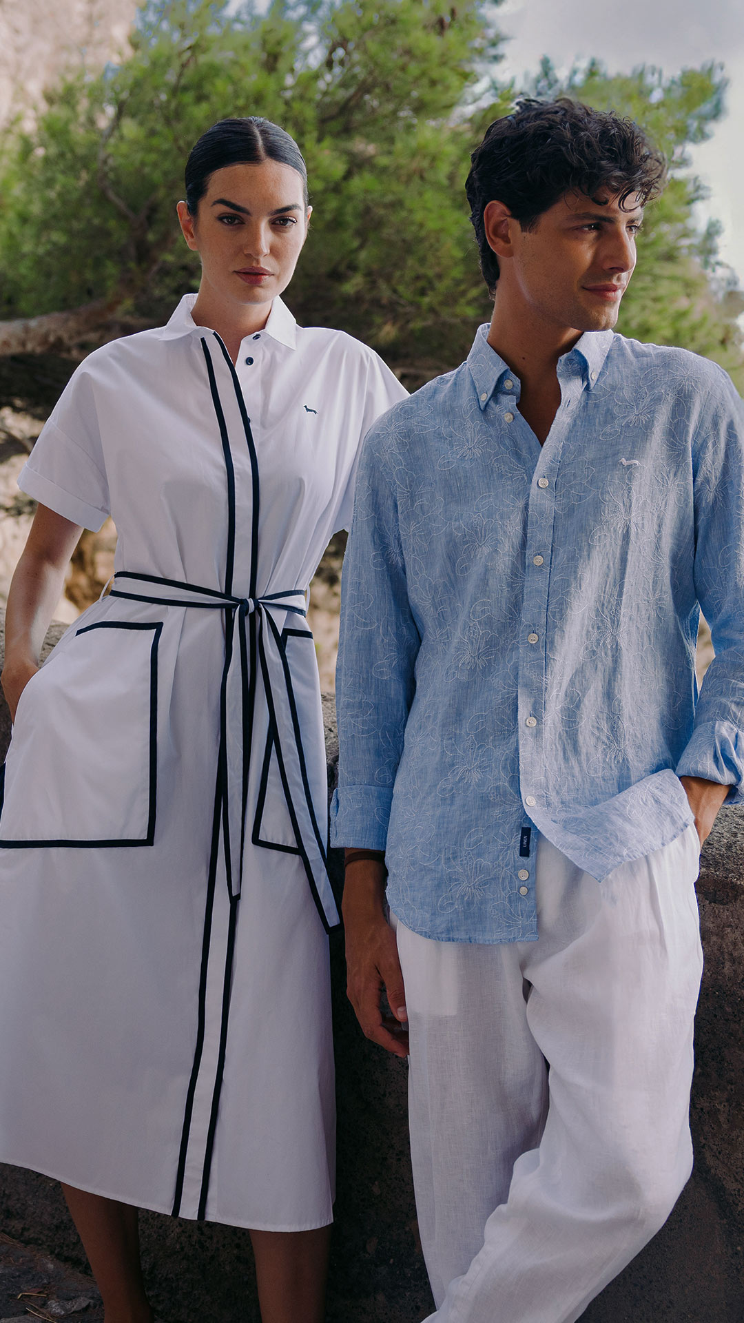 Donna in abito bianco con profili neri accanto a uomo in camicia azzurra e pantaloni bianchi