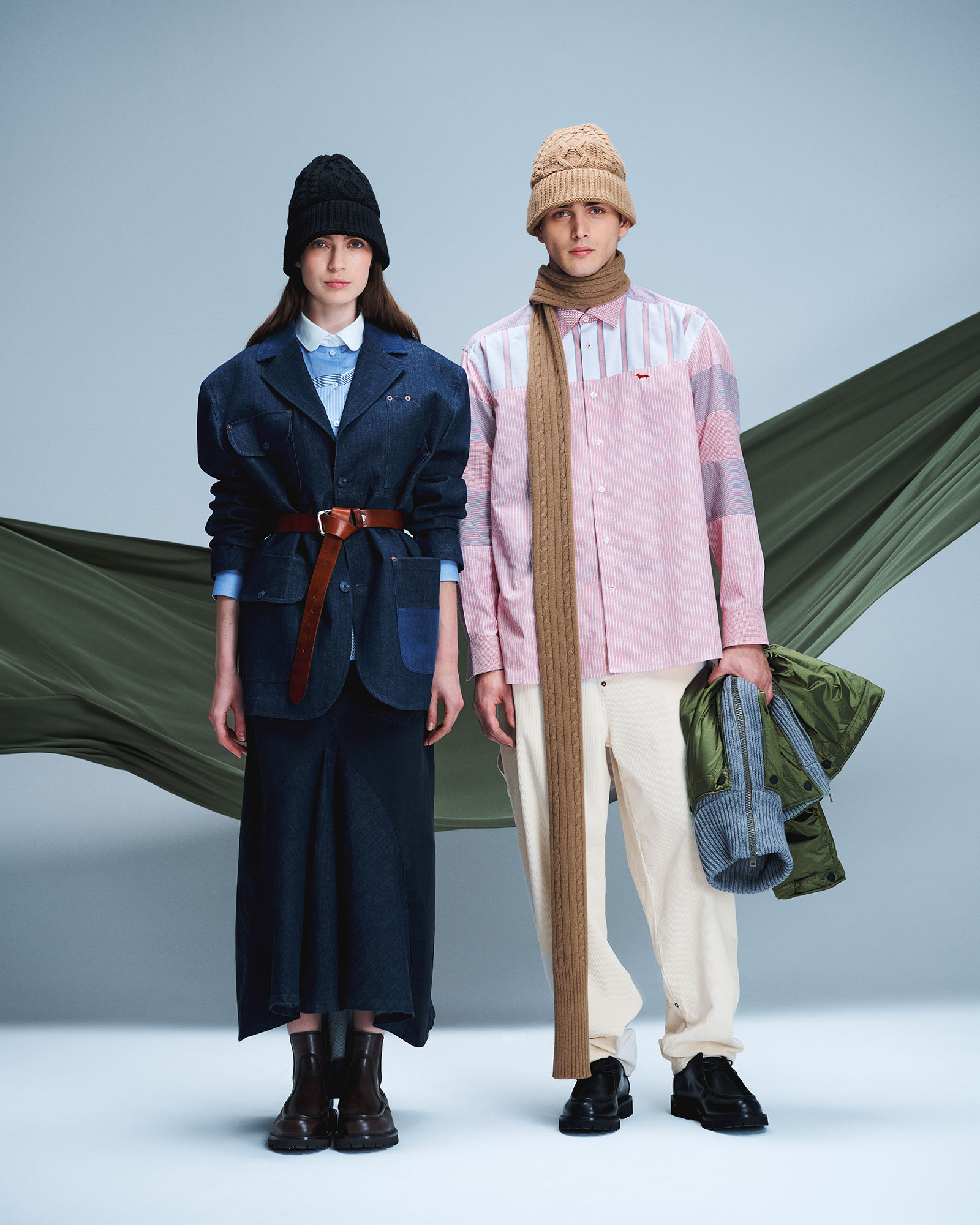 Woman and man in denim and shirting; she wears denim blazer and skirt, he wears patchwork shirt and light trousers