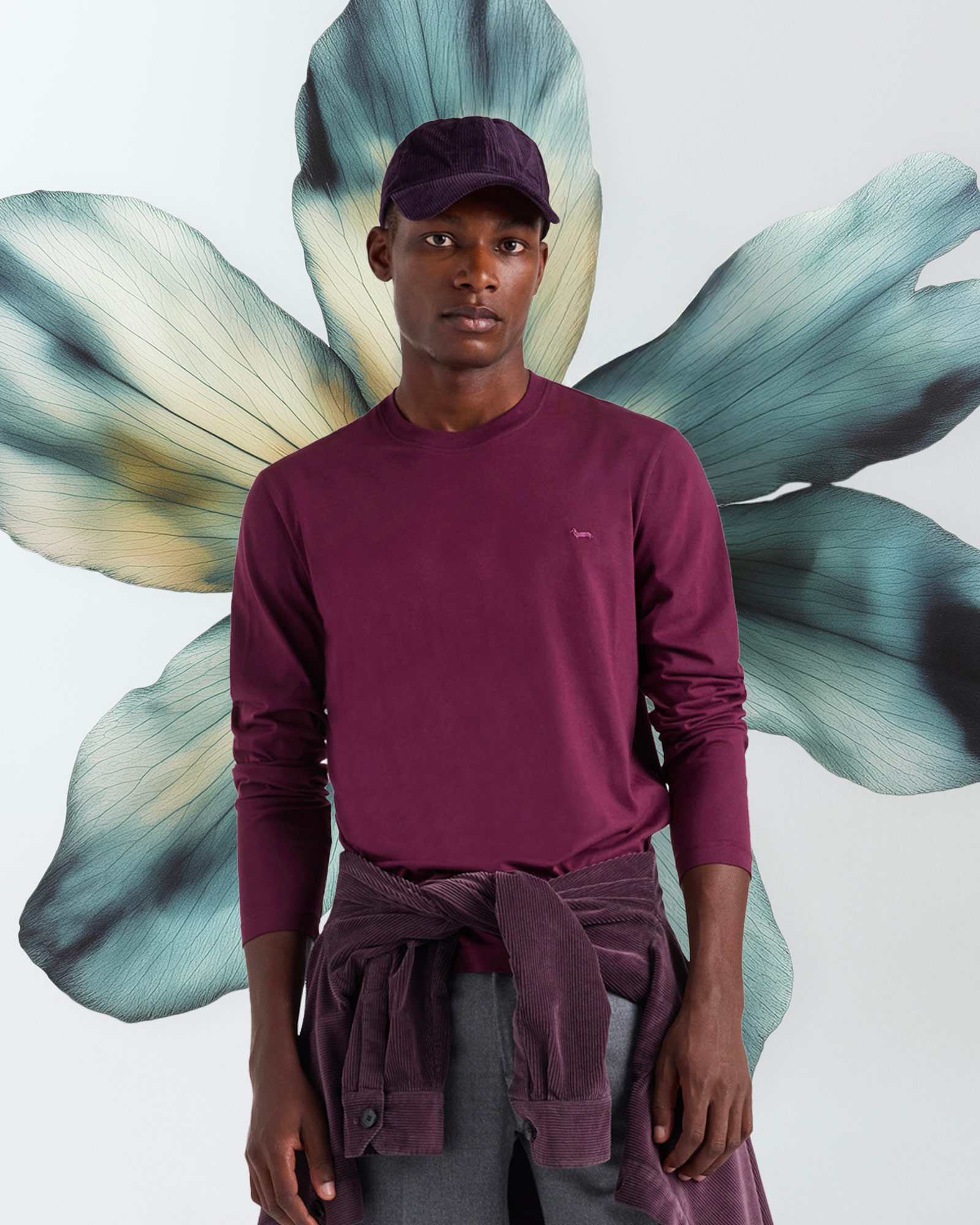 Man wearing a burgundy long-sleeve t-shirt with a corduroy shirt tied around his waist.