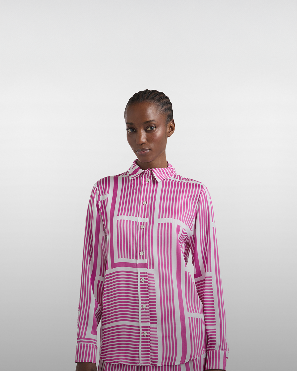 Persona in piedi davanti a grande fiore stilizzato su sfondo chiaro