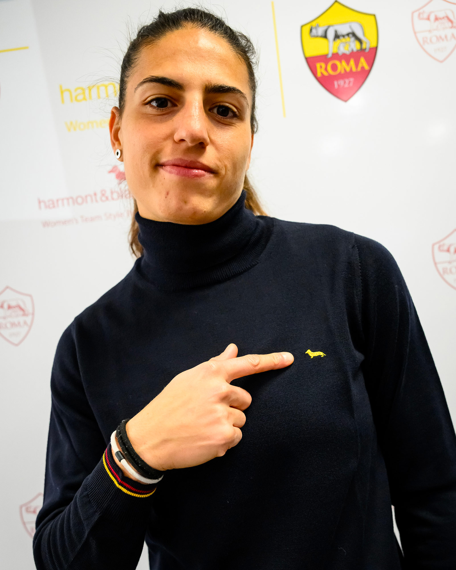 Donna con dolcevita blu navy che indica il logo giallo.