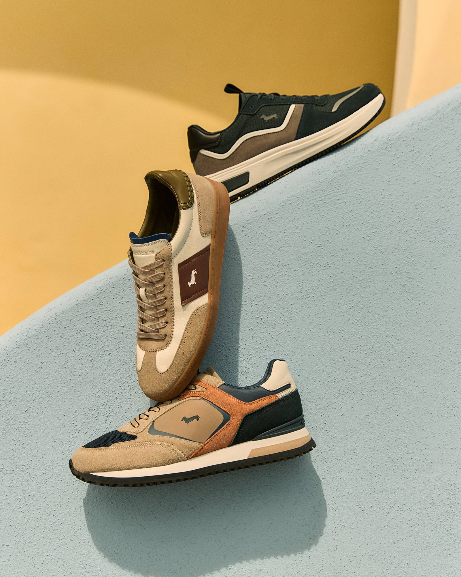 Three pairs of leather and fabric sneakers in neutral tones.