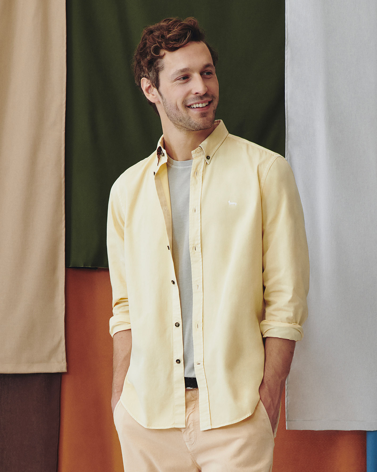 Model wearing a yellow shirt with light t-shirt and beige trousers.