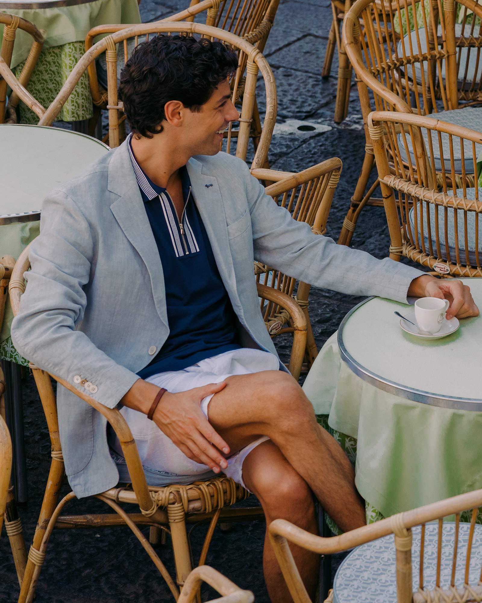 Man in light grey blazer sitting at café with coffee