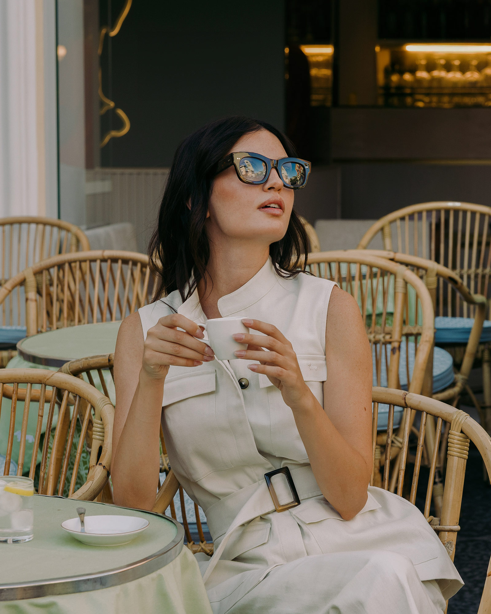 Woman with sunglasses drinking coffee outdoors