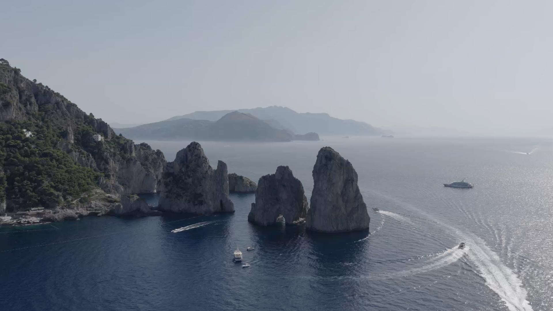 Aerial view of Capri's Faraglioni rocks with boats on the sea
