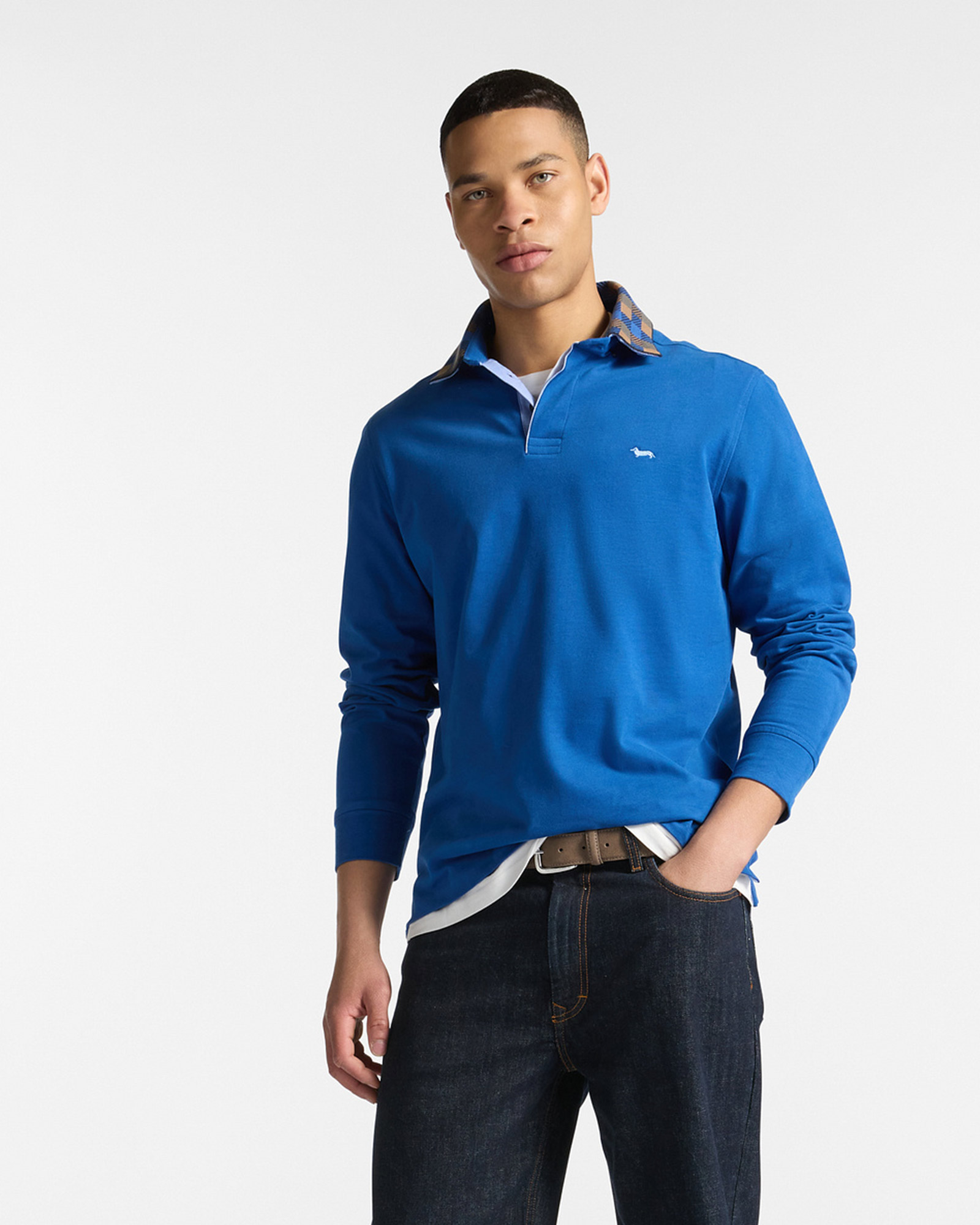 Hombre con polo azul de manga larga con cuello en contraste, combinado con vaqueros oscuros