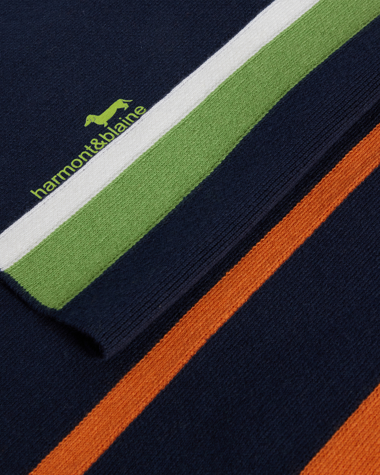 Detalle de bufanda de lana azul con rayas verdes, blancas y naranjas y logo Harmont & Blaine